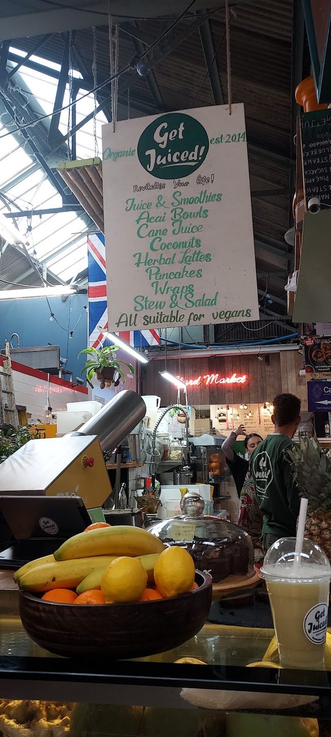 Looking up into the market roof above the stall, fruit bowl and takeaway cup below