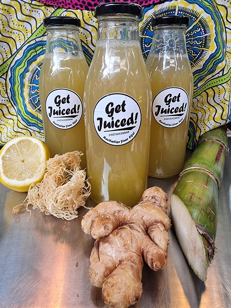 Bottled juices lined up beside lemon, ginger and sugar cane