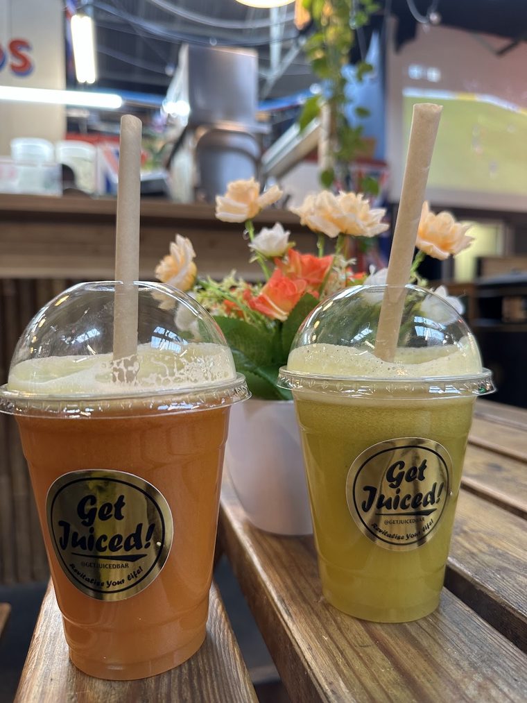 Orange and green juices in takeaway cups
