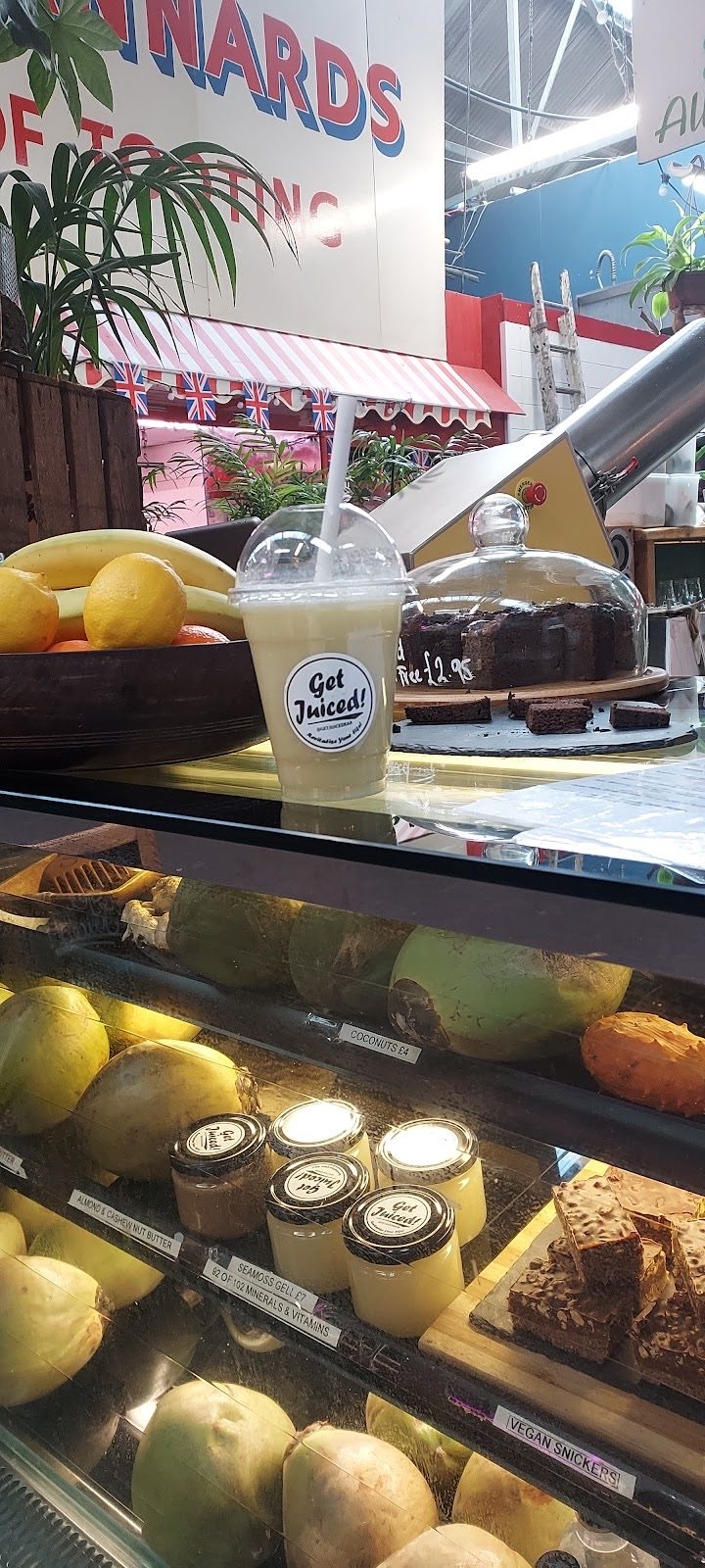 Cake under a glass dome in the chilled cabinet with coconuts and mangoes